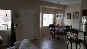 Un coin repas avec une table et des chaises, un réfrigérateur et une porte.