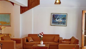 A living room with a brown sofa set, a coffee table, and a painting on the wall. - Anatoli Apartments (Hersonissos)