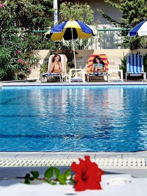 A swimming pool with lounge chairs and umbrellas. - Anatoli Apartments (Hersonissos)