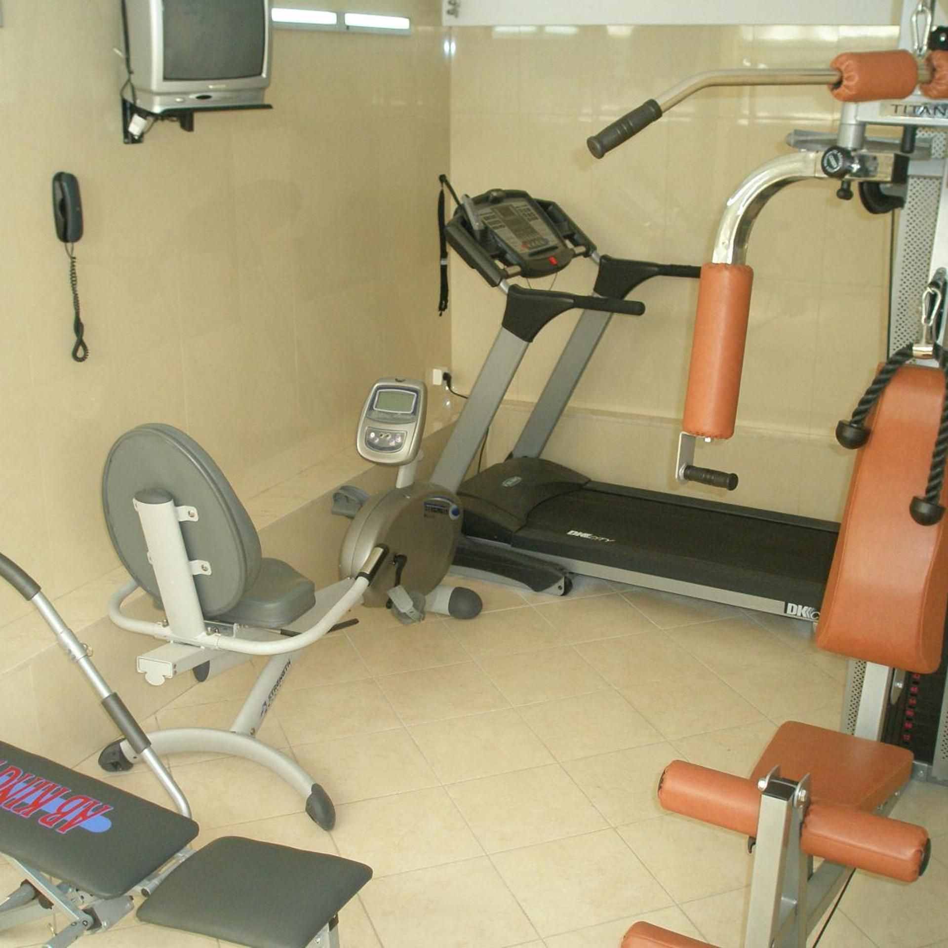 A gym with a treadmill, weight bench, and exercise equipment.