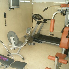 Ein Fitnessstudio mit Laufband, Gewichtshebel und Trainingsgeräten.