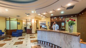 A hotel lobby with a reception desk, seating area, and a patterned floor. - Tolon Holidays (Nafplio)