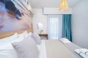A hotel room with a bed, a bedside table, a mirror, a window with curtains, and a wall-mounted air conditioner. - Nefeli Hotel (Thasos)