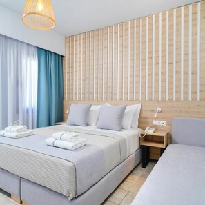 A hotel room with a large bed, bedside tables, a telephone, and a wall-mounted light fixture. - Nefeli Hotel (Thasos)