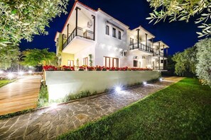 A two-story building with a balcony, a stone pathway, and a well-lit garden area. - Nefeli Hotel (Thasos)