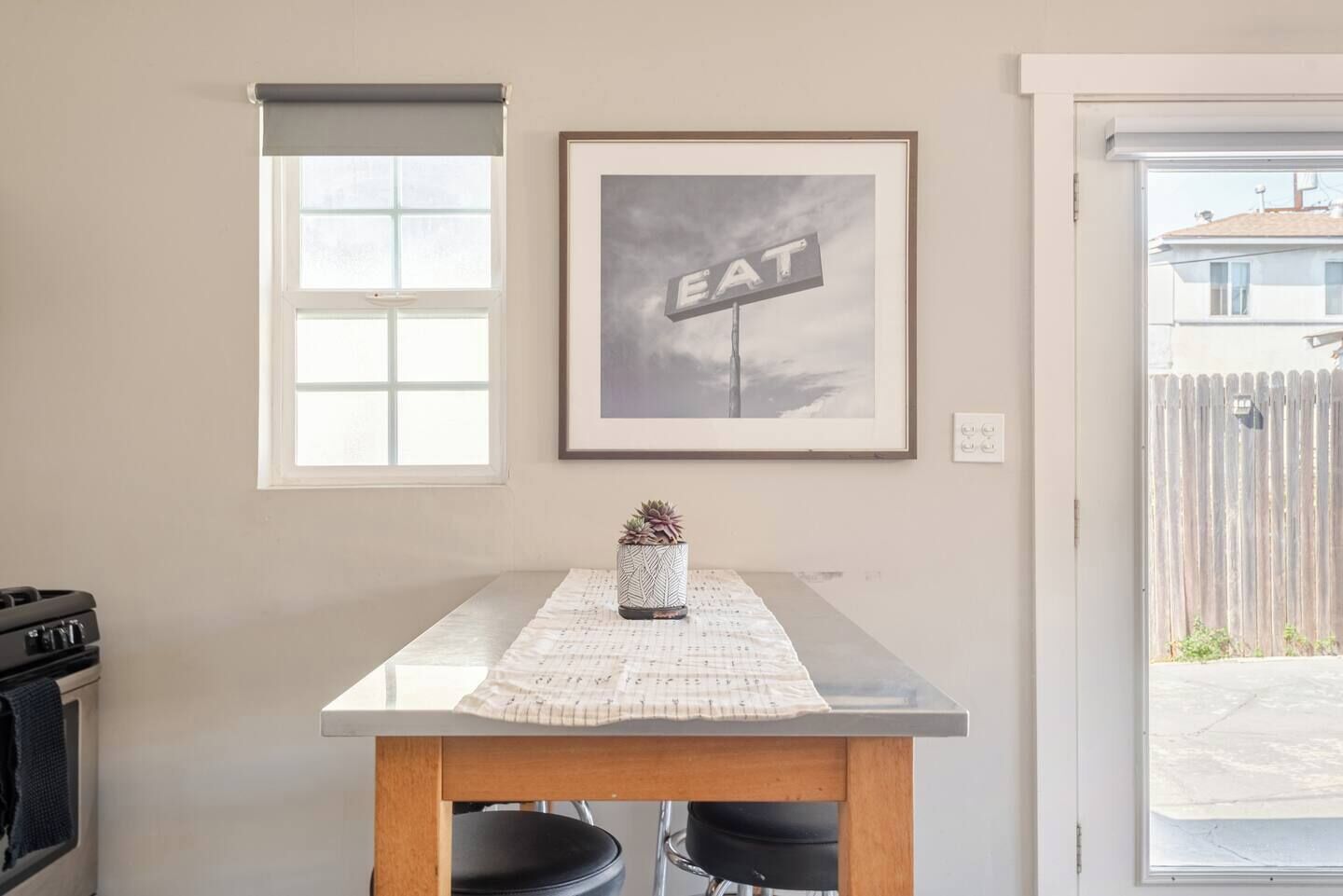 Uma cozinha com uma mesa de jantar, um quadro na parede e uma janela.