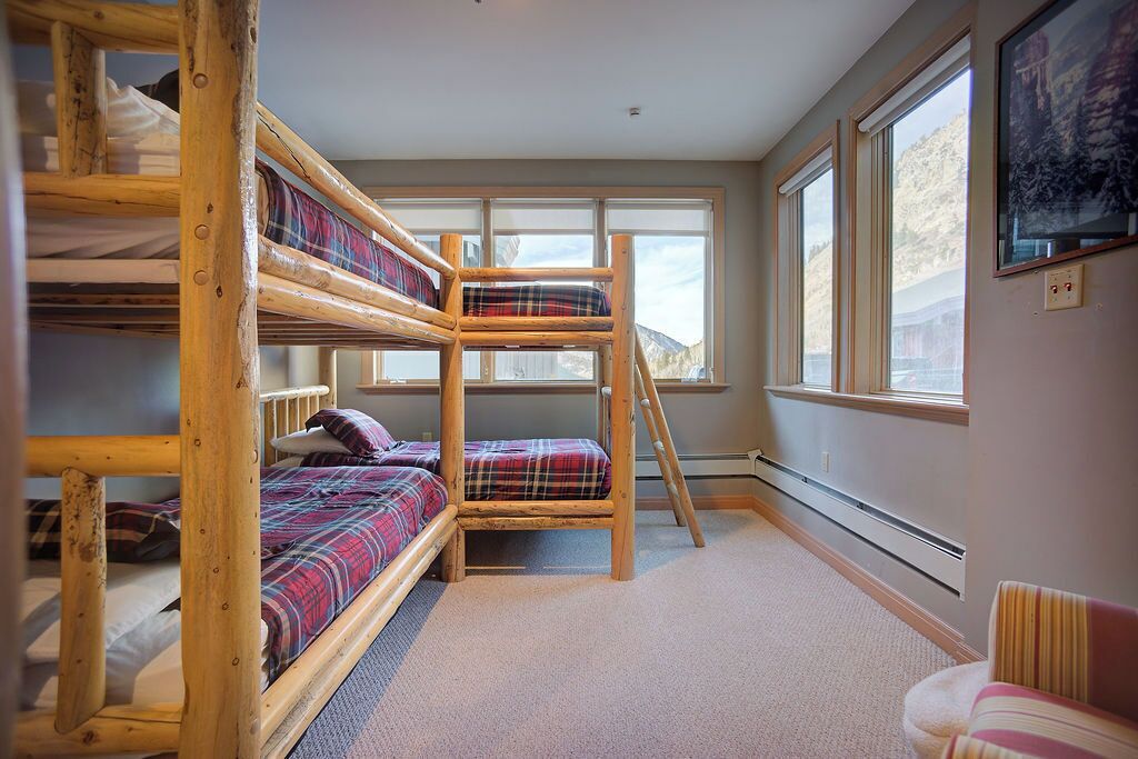 A bunk bed room with a view of mountains through large windows.