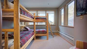 A bunk bed room with a view of mountains through large windows.
