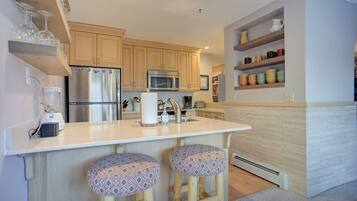 A modern kitchen with wooden cabinets, stainless steel appliances, and a central island with stools.