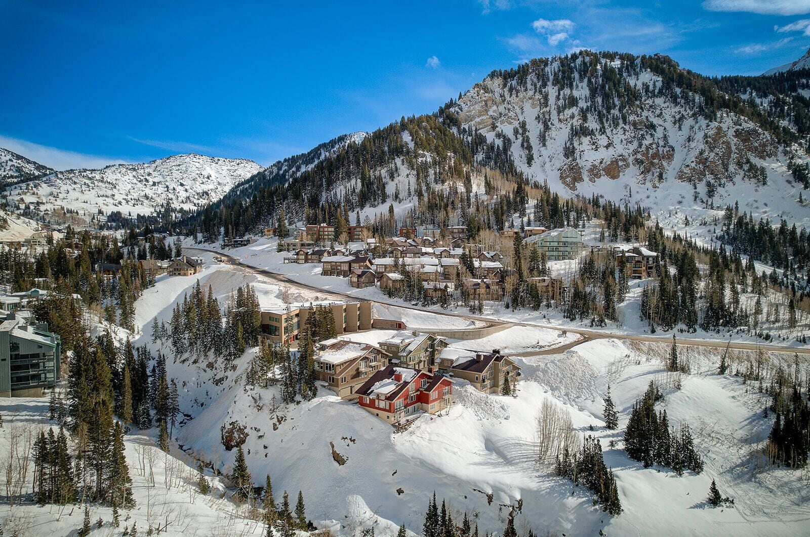 A snow-covered mountain town with a mix of residential and commercial buildings, including a prominent red building in the center.