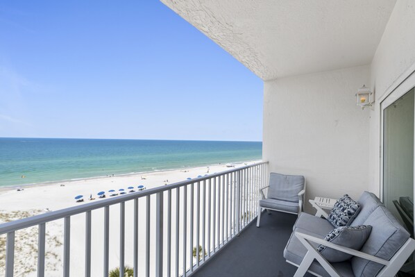 A balcony with a view of the beach and ocean.