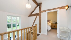 A room with a wooden staircase, a large window, and a door leading to another room. - The Hop Kiln and The Hayloft are two unique and attractive holiday lets (Monkland nr Leominster)