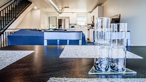 Une cuisine moderne dotée d’un îlot central, d’un escalier et d’un coin repas avec une table dressée pour quatre personnes.