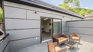 Une terrasse extérieure moderne, dotée de meubles en osier et d’une porte vitrée donnant sur un espace intérieur.