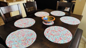 Une table à manger avec six sets de table ronds, un bol décoratif et un plateau en bois foncé.