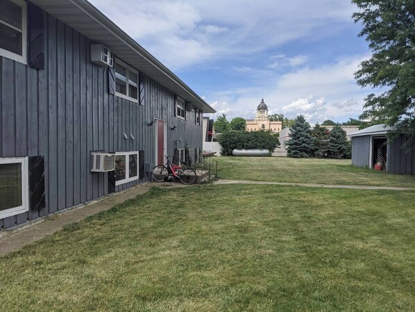 A building with a large lawn, a bicycle, and a distant building with a clock tower. - Centrally Located on Pawnee (Pierre)