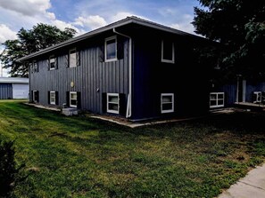 A two-story building with a dark exterior, multiple windows, and a visible front yard. - Centrally Located on Pawnee (Pierre)