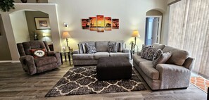 Relax in a cozy seating area with a comfortable armchair and sofa, complemented by a dark patterned rug and wall art.