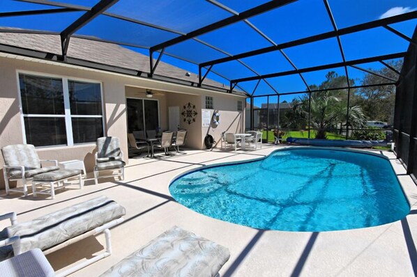 Relax by the pool surrounded by lounge chairs and tables, with a clear view of the surrounding neighborhood.