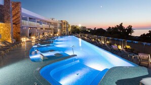 A swimming pool with a modern design, surrounded by lounge chairs and a stone wall. - Sirenis Club Aura (Sant Josep de sa Talaia)