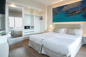 Un dormitorio moderno con una cama grande, armario empotrado y un cuadro de una playa tropical.