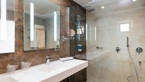A modern bathroom with a large mirror, two sinks, a shower, and a glass-enclosed shower area. - Sirenis Club Aura (Sant Josep de sa Talaia)