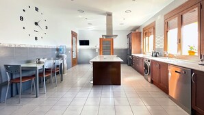 Uma cozinha moderna com uma ilha central, eletrodomésticos embutidos e uma área de jantar com cadeiras e mesa.