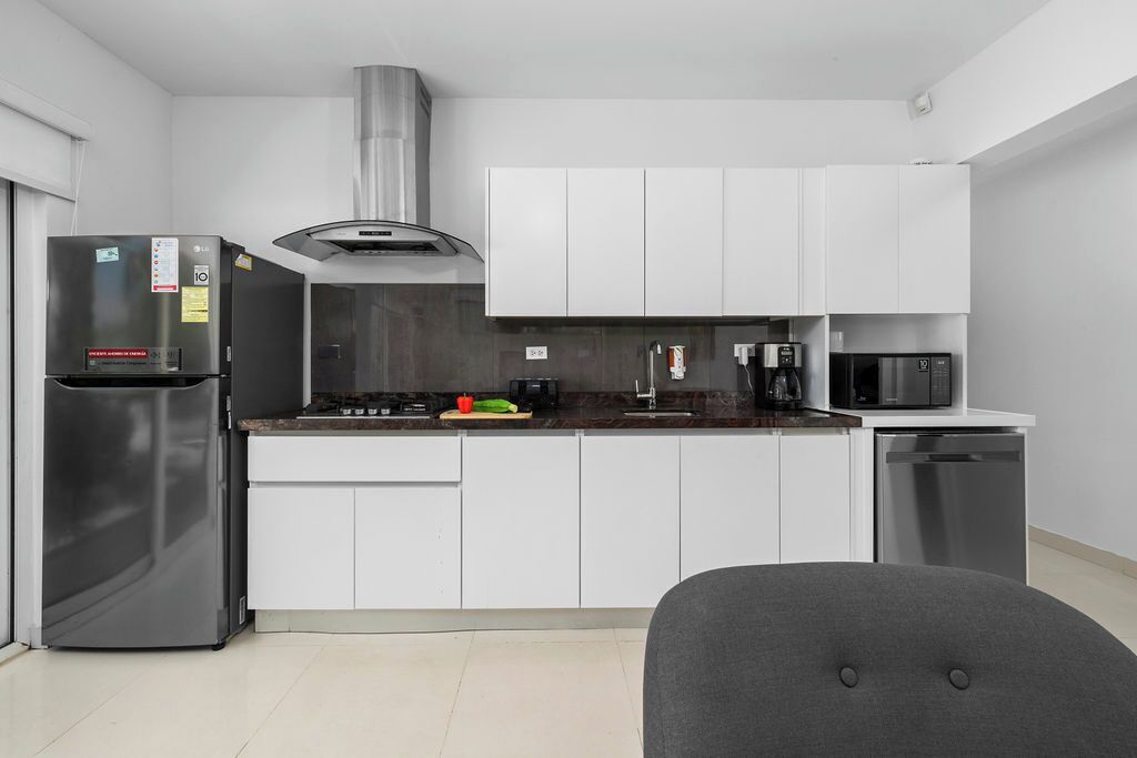 Una cocina moderna con armarios blancos, un refrigerador de acero inoxidable, un microondas y un lavavajillas.