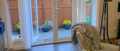 Una habitación con puerta de vidrio corredera que da a un patio trasero, un sillón blanco y un perchero.