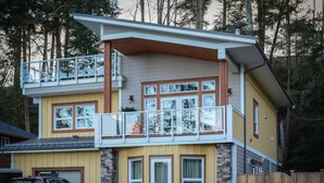 Ein zweistöckiges Haus mit Balkon, Garage und Holzzaun.