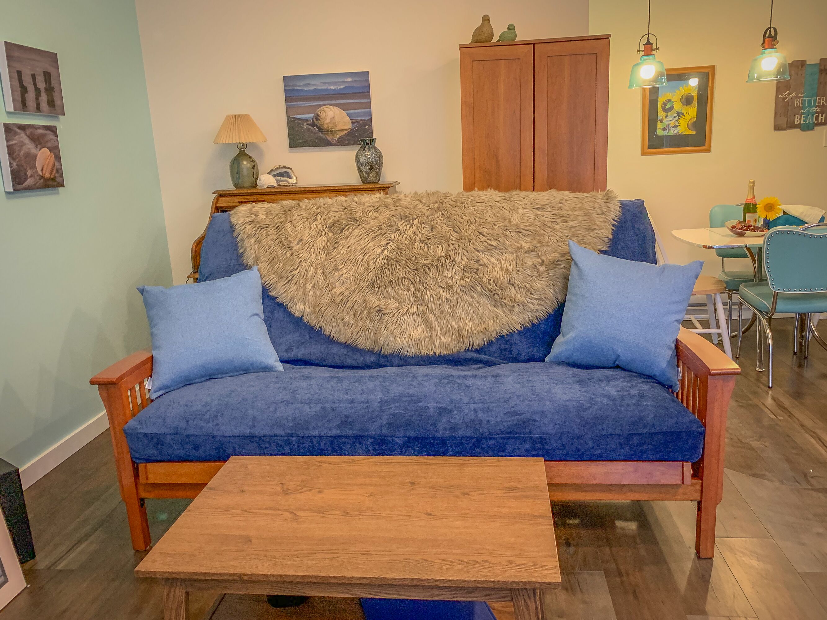 Una sala de estar acogedora con un sofá azul, una mesa de centro de madera y una alfombra mullida.