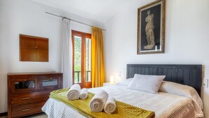 Un dormitorio con una cama, un aparador de madera, un cuadro y una ventana con cortinas.