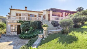 Una casa de dos pisos con fachada de piedra, un balcón y una escalera que lleva al piso superior.