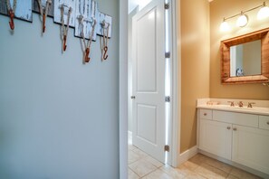 A bathroom with a white vanity, a wooden-framed mirror, and a light fixture above the mirror. - Scallop Pass (Port St. Joe)