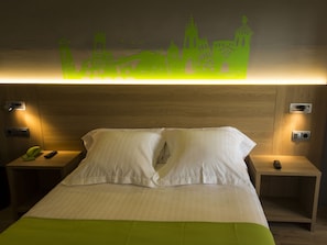 A hotel room with a bed, two bedside tables, a wall-mounted light, and a green bedspread. - Hotel Margarit (Girona)