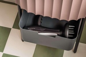 Una silla con un compartimento de almacenamiento integrado que contiene una plancha para el cabello y otros objetos personales.