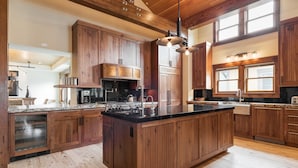 A spacious kitchen with wooden cabinets, a central island, and a large window providing natural light. - Woodside Villa (Park City)