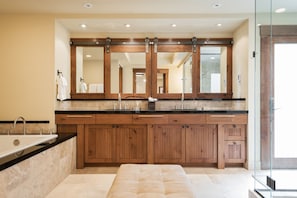 A modern bathroom with a large wooden vanity, a double sink, and a large mirror.