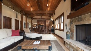 A spacious living room with a large wooden coffee table, a fireplace, and a cozy seating area. - Woodside Villa (Park City)
