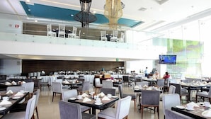 A spacious dining area with multiple tables and chairs, a second-floor balcony with seating, and a large screen displaying content. - Four Points by Sheraton Veracruz (Boca del Río)