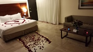 Une chambre d’hôtel avec un lit, un canapé, une table basse et un tableau au mur.