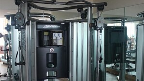 Une salle de sport avec un mur recouvert de miroirs, du matériel d’exercice et un ballon bleu pour faire de la gymnastique.