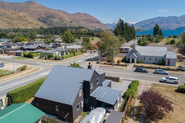A residential area with houses, a road, and mountains in the background. - Central Wānaka Retreat | Close to the lake! (Wānaka)