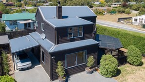 A two-story house with a garage, satellite dish, and a large window. - Central Wānaka Retreat | Close to the lake! (Wānaka)
