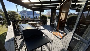 An outdoor patio with a grill, wooden deck, and a view of a church and mountains in the background. - Central Wānaka Retreat | Close to the lake! (Wānaka)