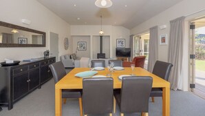 A dining area with a wooden table, black chairs, a black cabinet, a TV, and a fireplace.