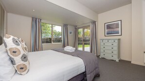 A bedroom with a bed, a dresser, and a window with curtains.