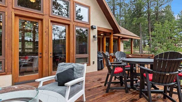 A wooden deck with outdoor furniture, including a table and chairs, and a hot tub.
