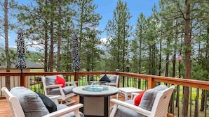 Una terraza con mobiliario exterior, jacuzzi y vista a un área boscosa.