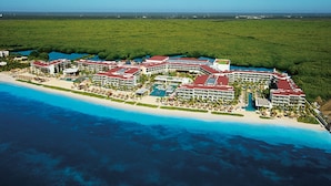 Vista aerea di un resort con diversi edifici, una spiaggia e un'ampia distesa d'acqua.